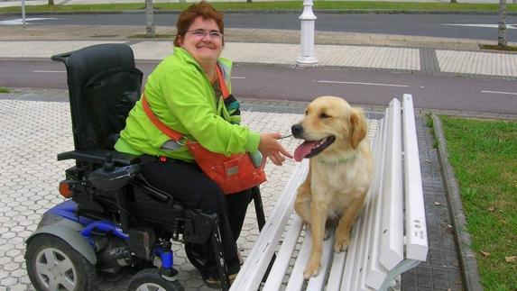 Una mujer en silla de ruedas juega con su mascota. 