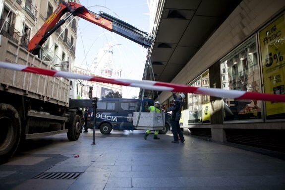 Dos operarios instalan ayer maceteros gigantes en las inmediaciones de la Puerta del Sol. :: Elvira Megías
