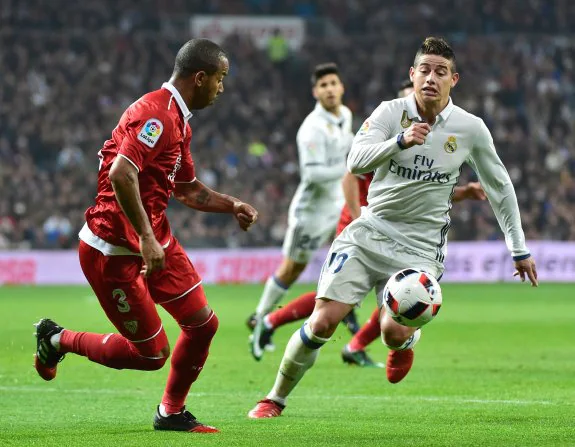 James Rodríguez, el triunfador de la noche en el Bernabéu, pugna por el balón con el defensa sevillista Mariano . :: afp