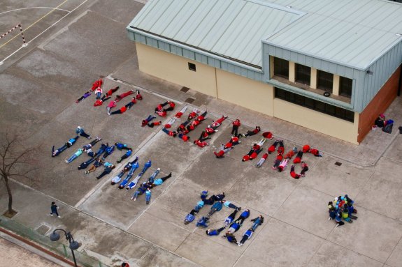 Alumnos de 5º (los de rojo) y de 6º (los de azul) escribieron un mensaje contra el acoso con sus propios cuerpos en el patio del colegio. 