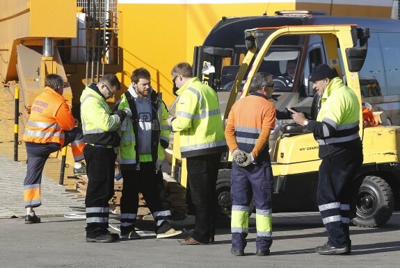 Trabajadores de carga y descarga en el puerto de Valencia conversan sobre su situación. :: jesús sánchez
