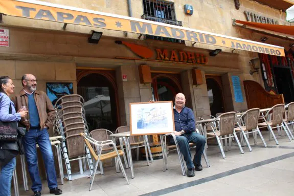 Juan Manuel Sáenz posa ante su bar, el Madrid, con un cuadro de la misma fachada de José Uríszar. 