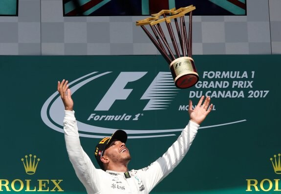 Lewis Hamilton lanza al aire el trofeo que le acredita como ganador del Gran Premio de Canadá. :: reuters
