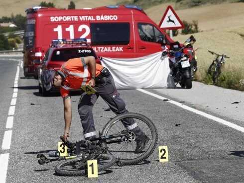 Un policía señala la bicicleta de un ciclista atropellado. :: 