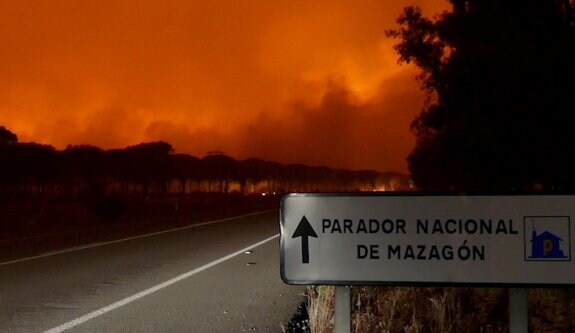 La carretera A-494, que une Mazagón y Matalascañas, permanecía ayer cortada al tráfico y cercada por el fuego. :: EFE
