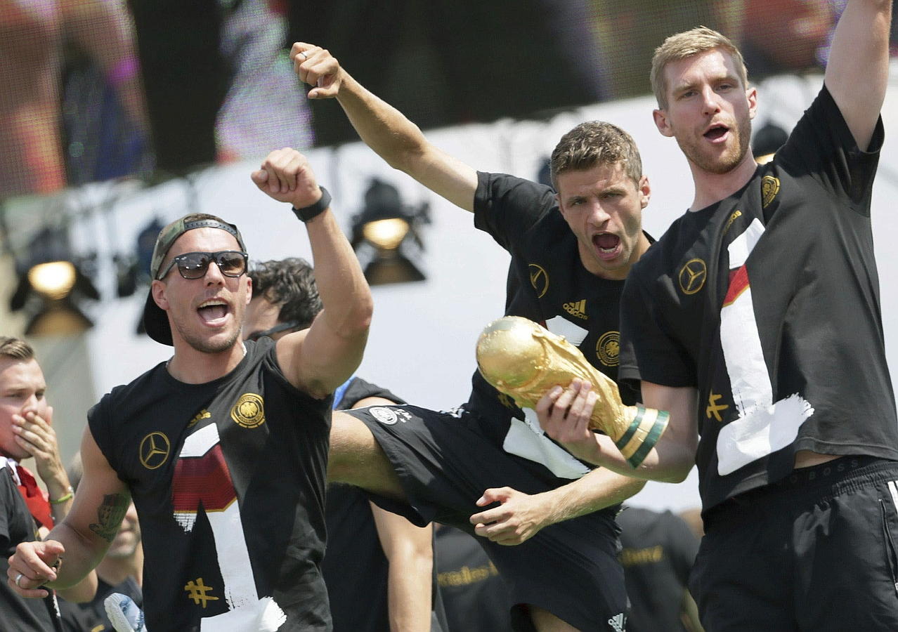 LA SELECCIÓN ALEMANA CELEBRA LA COPA DEL MUNDO CON MILES DE AFICIONADOS. Lukas Podolski (i-d), Thomas Mueller y Per Mertesacker celebran la Copa del Mundo con los aficionados durante la multitudinaria fiesta de bienvenida celebrada en su honor en la Puerta de Brandeburgo, en Berlín.