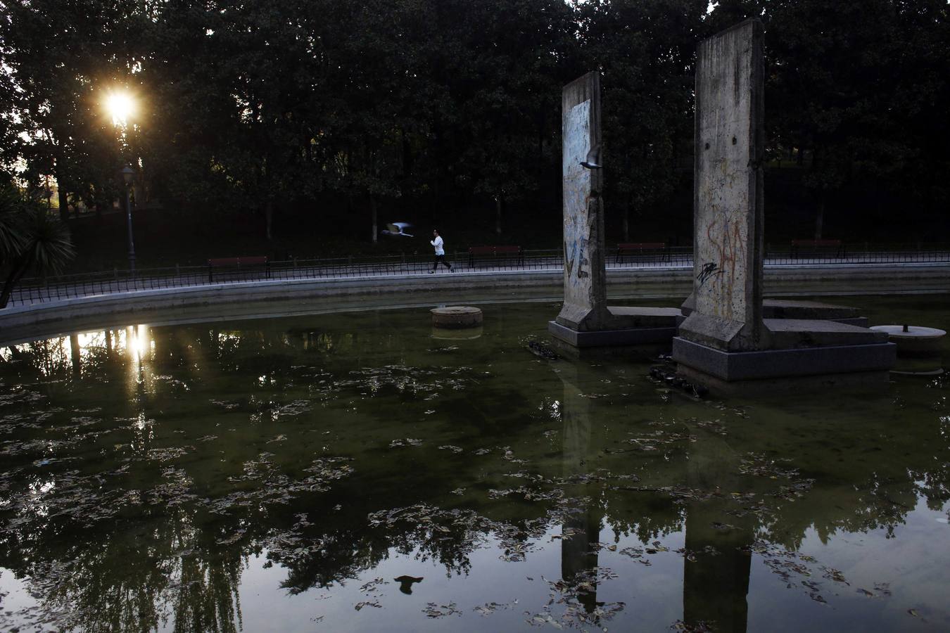 Una mujer corre al lado de una parte del Muro en el Parque de Berlín en Madrid.