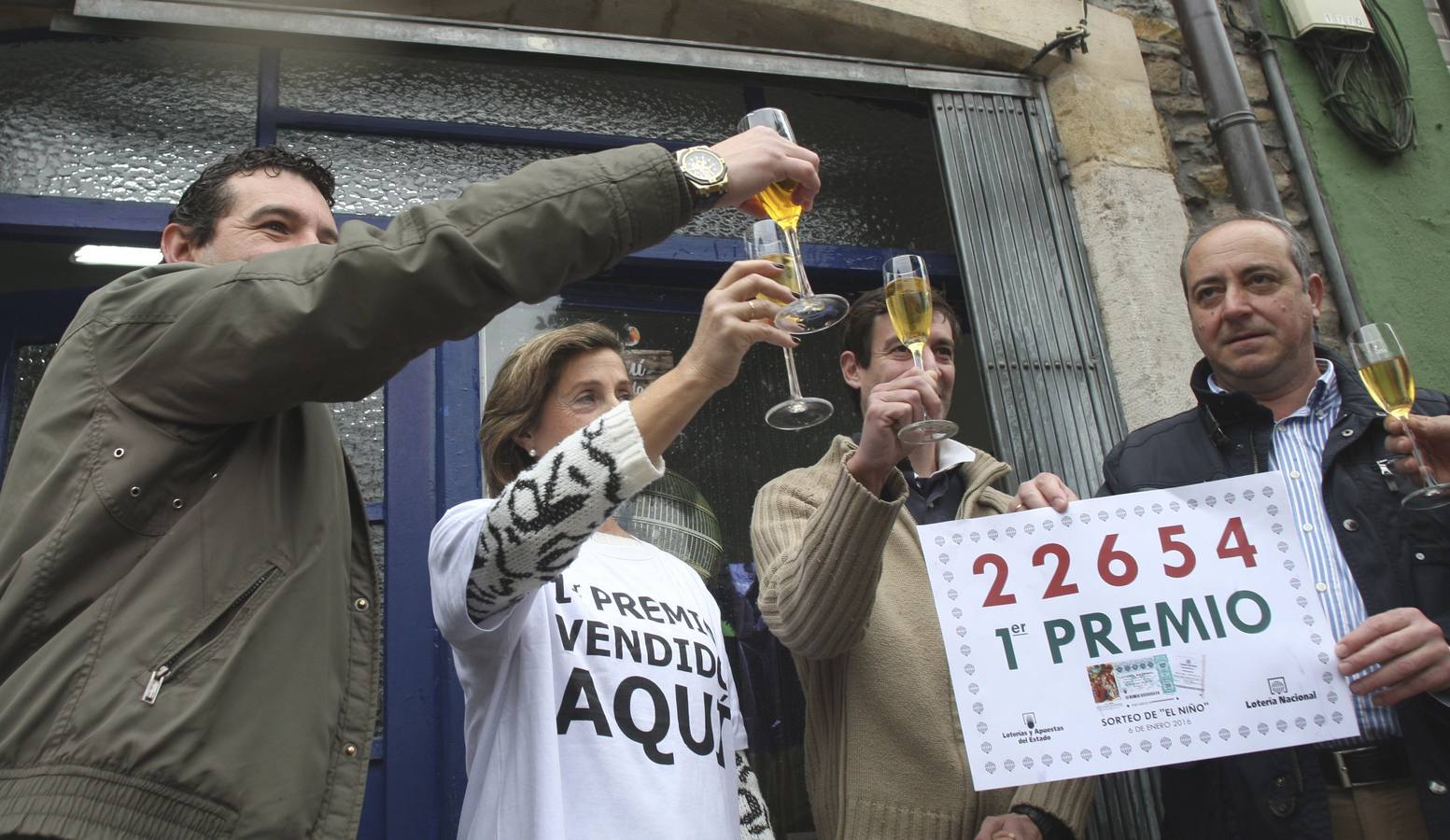 La dueña del despacho de loteria ubicado en la calle Profesor Pérez Pimentel,59, de Gijón, Isabel Rubiera (2i), celebra con sus vecinos haber vendido un décimo del 22654, agraciado con el primer premio.