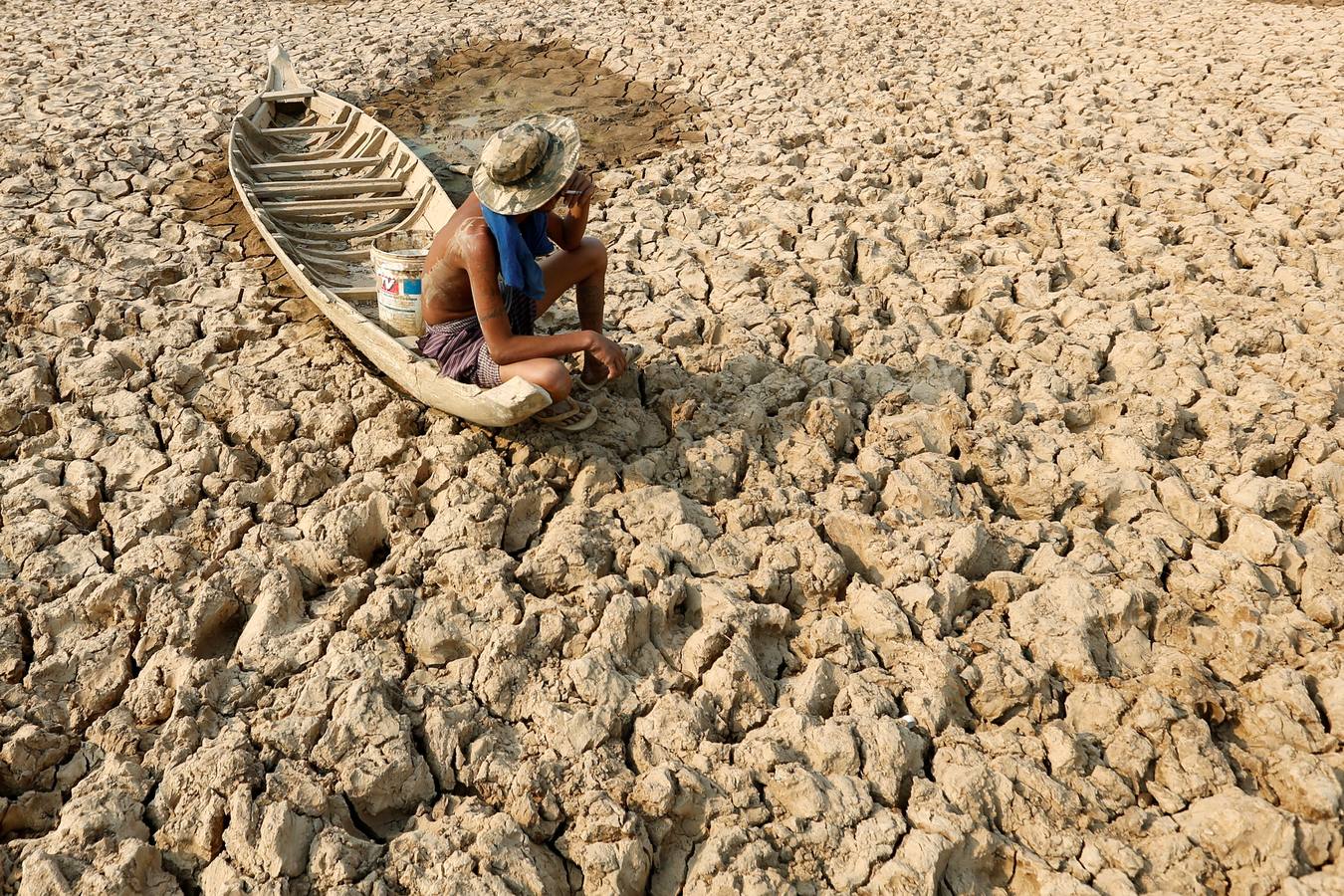 Un pescador se sienta a fumar en su barca en el estanque seco de Bak Angrout, en la provincia de Kandal (Camboya).