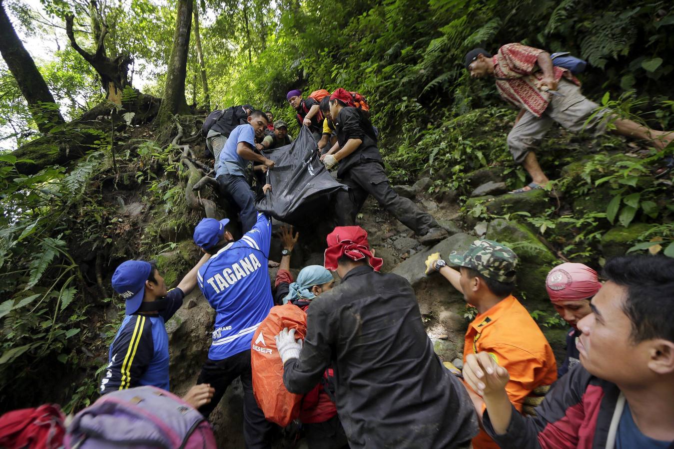 Miembros de los servicios de rescate recuperan el cuerpo de una víctima tras una riada en el bosque de Sibolangit en Deliserdang, en el norte de Sumatra, Indonesia, este lunes 16 de mayo de 2016. Al menos 20 personas permanecen desaparecidas después de que las fuertes lluvias provocasen este domingo una riada el cerca de una cascada popular entre los turistas de la región. Las víctimas son estudiantes de varias universidades de Medan, que pasaban el fin de semana acampados en la zona y que se vieron sorprendidos por la riada mientras visitaban el salto de agua.