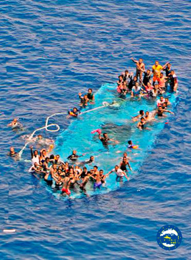 Inmigrantes y refugiados, en una barca semisumergida, poco antes de ser rescatados por la fragata española 'Reina Sofía', cerca de la costa libia.