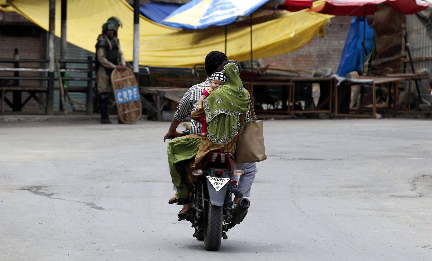 Una familia se desplaza en moto por el centro de Srinagar, la capital estival de la parte de Cachemira administrada por la India, hoy, 30 de julio de 2016. Las autoridades impusieron el toque de queda en los dos distritos meridionales de Cachemira y restricciones en varias zonas del valle después de que un centenar de jóvenes resultaran heridos en los enfrentamientos ocurridos durante una protesta que quería desafiar el toque de queda en varias zonas de todo Cachemira ayer, según informaron medios locales. Unos 50 civiles fueron asesinados tras las protestas convocadas por el asesinato del comandante Burhan Muzaffar Wani y dos colaboradores durante un tiroteo el pasado 8 de julio. EFE/Farooq Khan