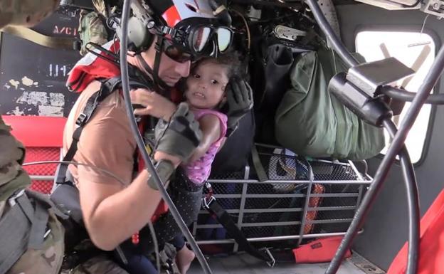 Una niña rescatada por un miembro de las fuerzas aéreas.