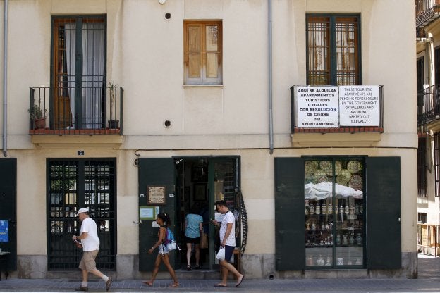 Unos turistas pasan junto a unos carteles que protestan por alquileres ilegales. 