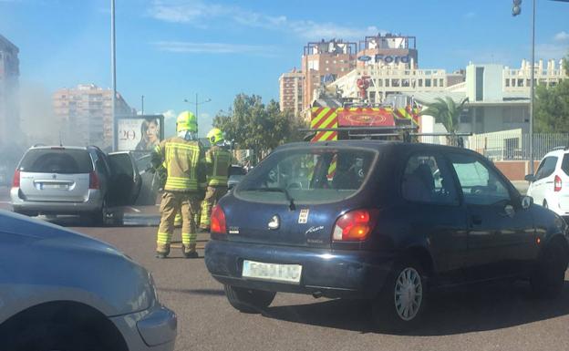 Los bomberos atendiendo el coche incendiado.