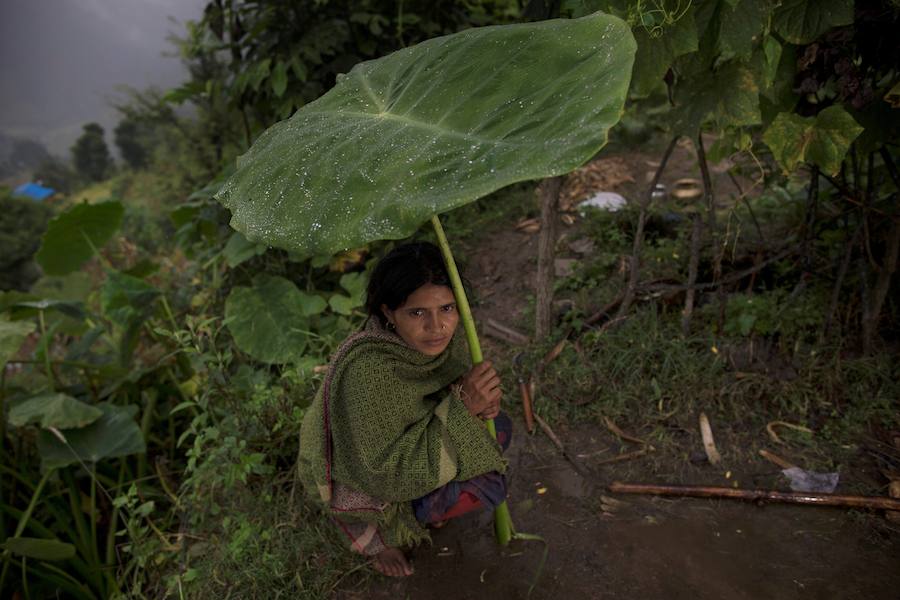 Pabitra Devi Jaisi, de 29 años, madre de cuatro niños, se cubre con una hoja de la lluvia mientras espera en la interperie a recibir comida a las puertas de su casa con motivo de su menstruación. 