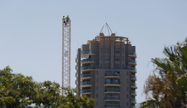 Operarios en lo alto de una grúa en proceso de montaje para la construcción de un edificio en Valencia. 