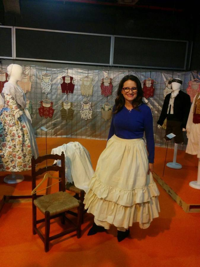 La vicepresidenta del Consell, Mónica Oltra, ha visitado la feria Fiesta y Boda y se ha probado una pieza de indumentaria valenciana en un expositor.