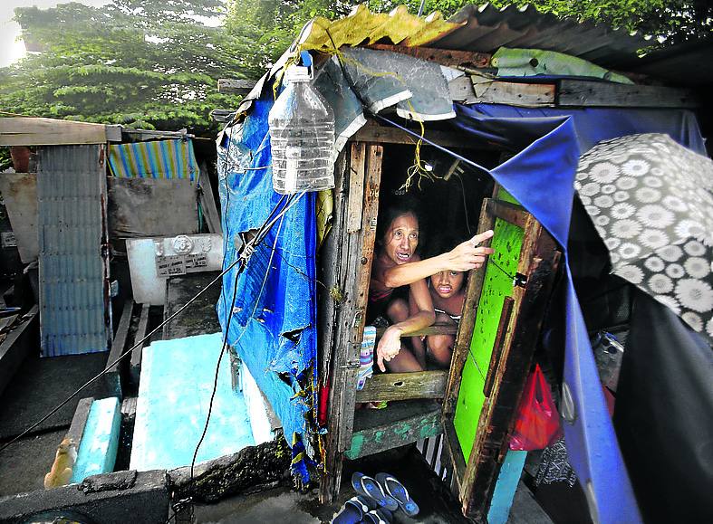 Dos residentes del cementerio público de Pasay City, asomados a la puerta de su chabola. Las viviendas se construyen sin orden ni concierto con tablas y uralita.