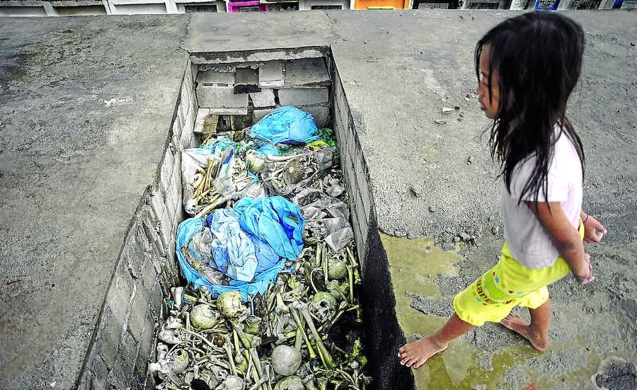 Una niña se dispone a saltar sobre un montón de huesos abandonados en el cementerio de Navotas, al norte de la capital. Los nichos se alquilan por un periodo de tiempo y luego, si no se reclaman, se amontonan en cualquier esquina. Otros restos ocupan su lugar.