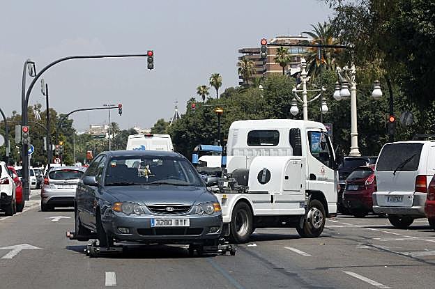 Una grúa retira un coche en el paseo de la Alameda. 