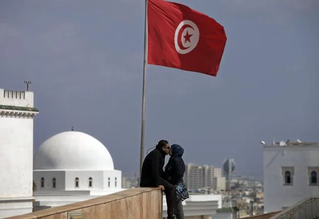 Una pareja se besa en una azotea, bajo una bandera de Turquía.  