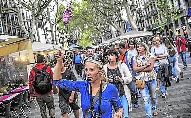 Una guía señala el camino a un grupo de turistas en la siempre masificada Rambla de Barcelona. :