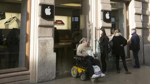 Varias personas, ayer, en una de las puertas de acceso a la tienda de Apple en la calle Colón de Valencia. 