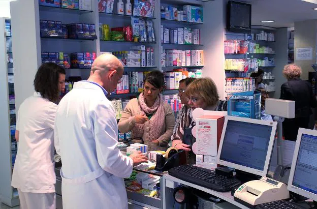 Profesionales y pacientes, en una farmacia. 