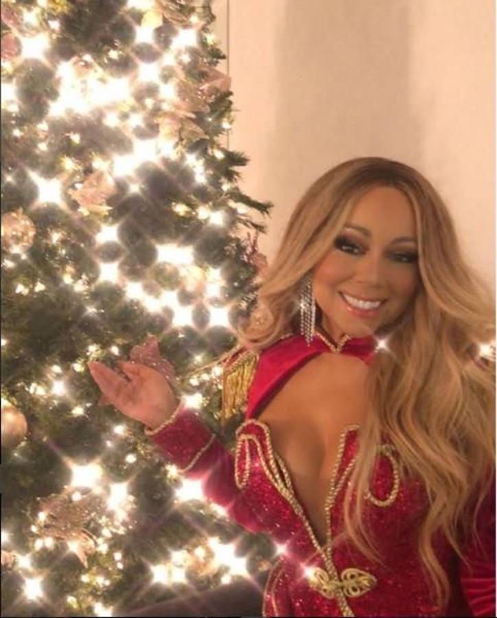 Mariah Carey, erigida en Mama Nöel planetaria desde que estrenó su rentable ‘All I want for Christmas is you’, felicita a sus seguidores desde un abeto cegador, enfundada en una chaqueta de presentador de circo con prominente escote.