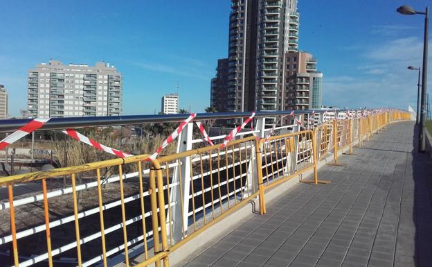 Vallas con bridas de plástico protegen la barandilla de la pasarela que une Nazaret y la Ciudad de las Artes. 