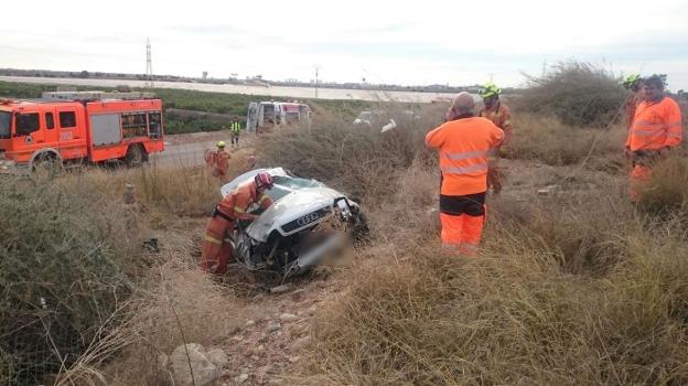 Varios bomberos junto al vehículo accidentado . 