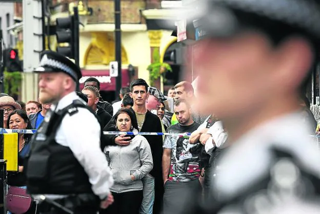 Los curiosos se agolpan tras la barrera policial después de un ataque en Londres. 