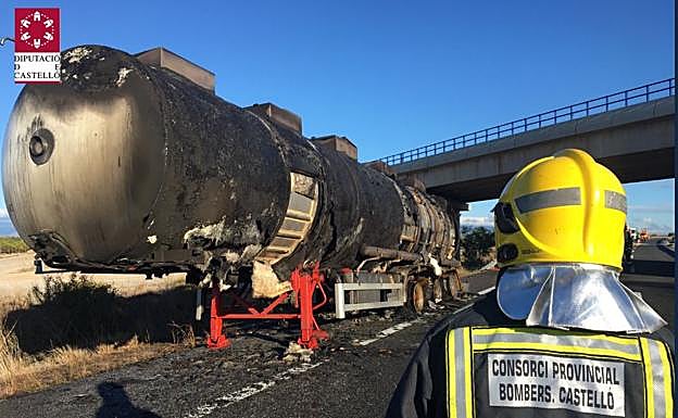 Un bombero trata de refrescar el camión incendiado. 