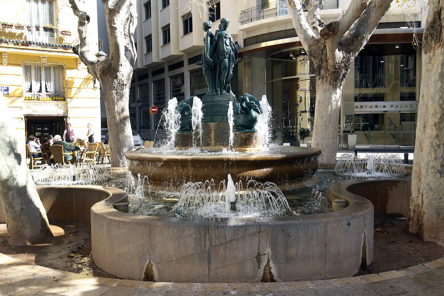 5.- Fuente de las Tres Gracias | Estuvo en la plaza de Las Barcas (que luego se llamó calle del Pintor Sorolla), se inauguró en 1852 y finalmente se trasladó a la plaza Rodrigo Botet, donde permanece en la actualidad. De piedra y hierro colado, tiene, sobre un pedestal, el grupo de las tres ninfas o gracias, unidas por las espaldas y con un tritón, como remate, que vierte el agua sobre un plato, hoy inexistente, cayendo el líquido del plato sobre la taza de piedra circular así como el de los cuatro ánades dispuestos para servir el agua al público, en su día. Esta fuente fue restaurada en el año 2000, pues durante mucho tiempo una de las figuras femeninas perdió su cabeza.