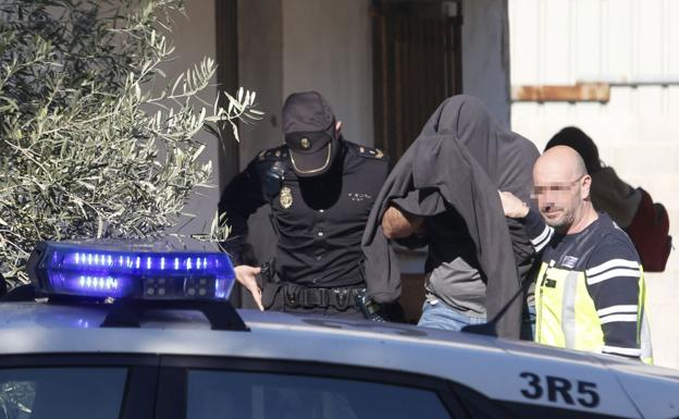 Dos agentes trasladan al asesino confeso (con el rostro tapado) a un vehículo policial. 