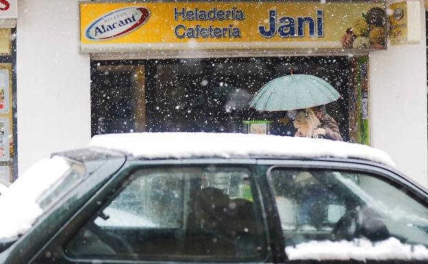 Dos personas pasan junto a una heladería de Utiel, donde la nevada ha obligado a suspender las clases.