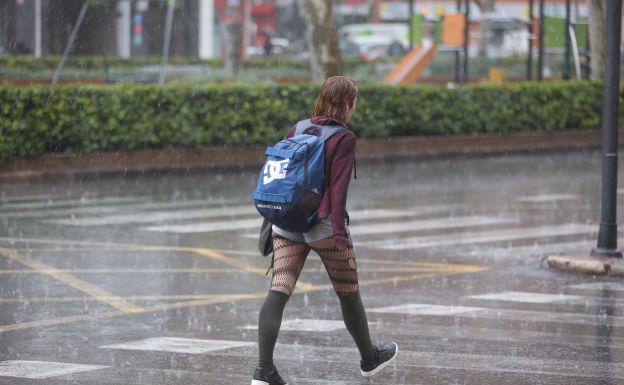 Una joven camina bajo la fuerte lluvia hoy en Valencia.