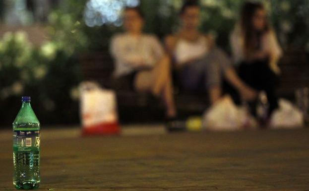 Grupos de jovenes practicando el botellon antes de entrar a una discoteca. 