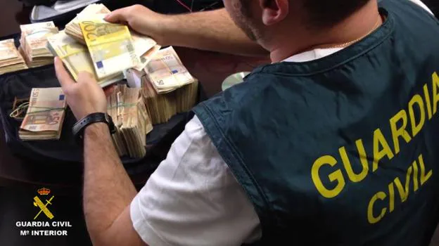 Un guardia civil cuenta billetes intervenidos en una operación antidroga. 