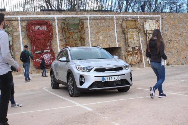 Visitantes junto a los coches que cuelgan junto a uno de los parkings.