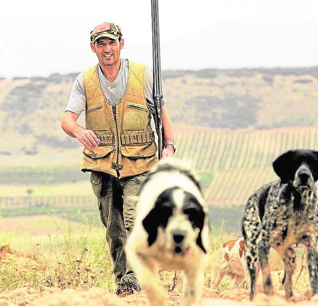 Un cazador avanza por el campo junto a sus perros. 