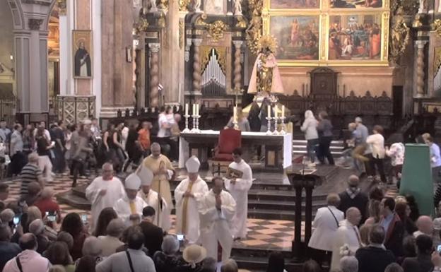 Instante en el que los fieles corren a tocar a la Virgen durante la Misa.