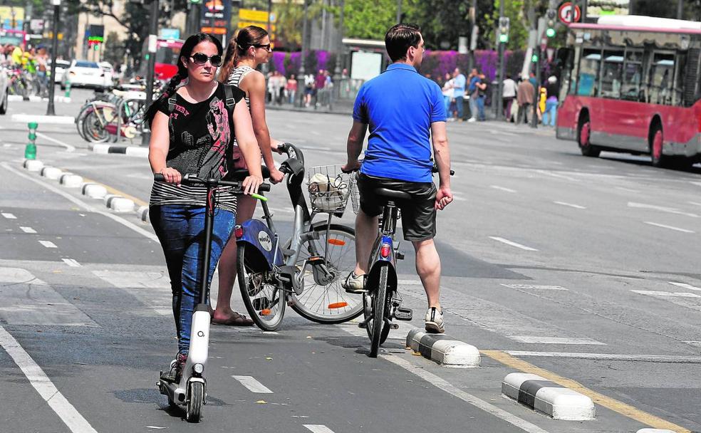 Usuarios circulan con sus patinetes por el carril bici y por un paso de peatones. 