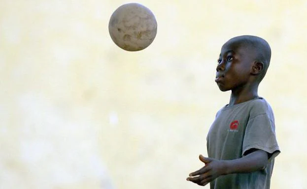 Un niño africano juega con una pelota.