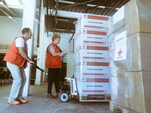Técnicos de Cruz Roja, descargando ayer material para la atención de los inmigrantes en la base del Alinghi en el puerto de Valencia. 
