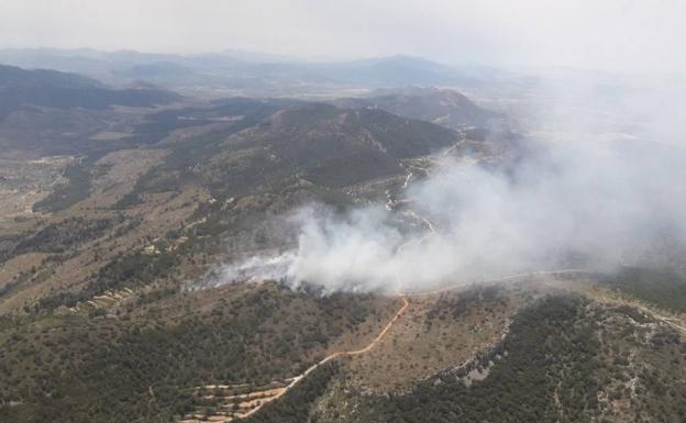 Los bomberos trabajan en la extinción de un incendio en una zona de montaña entre Ibi y Onil