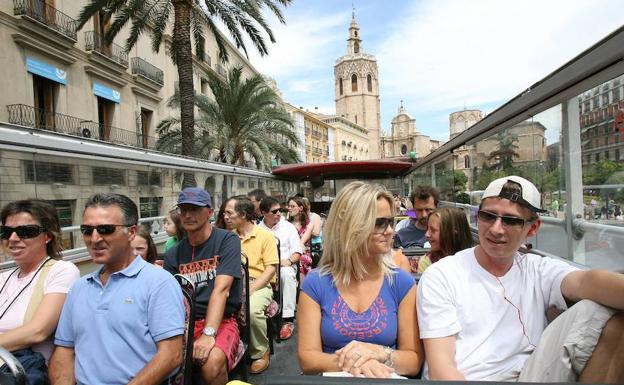 Turistas realizado el recorrido de un bus turístico por la ciudad de Valencia