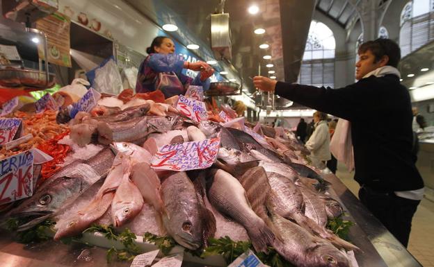 Un cliente compra pescado en un puesto del Mercado Central de Valencia