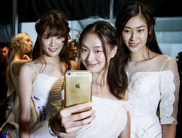 Tres jóvenes chinas se hacen selfi con una un Iphone, en la semana de la moda de Shanghái. 